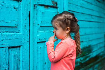 the little girl looks at an old door, beautiful turquoise background of woodの写真素材