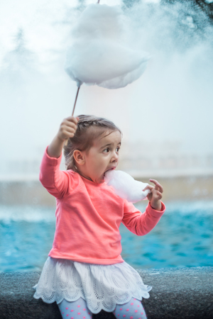 the emotions of a little girl with cotton candy near the fountainの写真素材