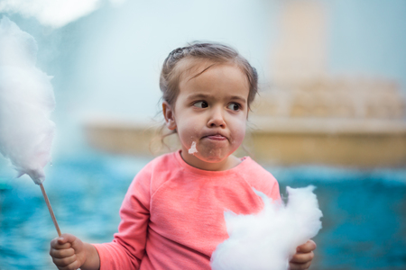 the emotions of a little girl with cotton candy near the fountainの写真素材