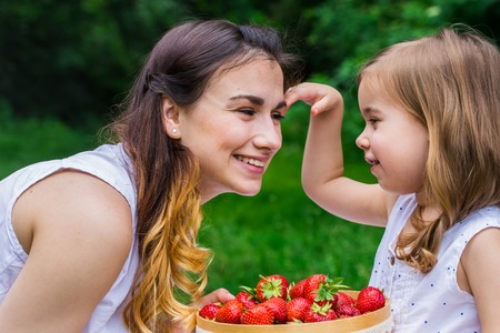 mother and daughter on a picnic and eat strawberriesの写真素材