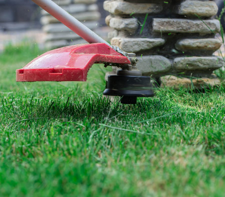 manual lawn mower on the background of green grass, cut grass in not accessible places