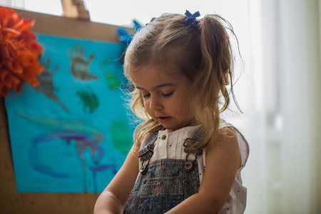 the little girl in the painting process at the easelの写真素材