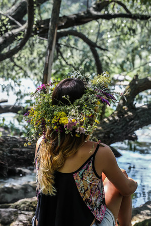 beautiful girl in a wreath of flowers on the banks of the river, on a Sunny day. The pagan rite of a young girl of Midsummer. Earth Dayの写真素材