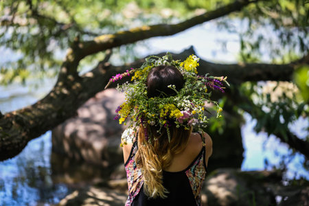 beautiful girl in a wreath of flowers on the banks of the river, on a Sunny day. The pagan rite of a...