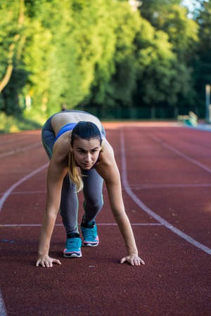 sports beautiful girl on the treadmill ready to run a big stadium, closeupの写真素材