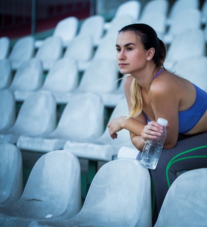 beautiful sporty girl drinking water after running in the stadium, close-up, young sporty womanの写真素材