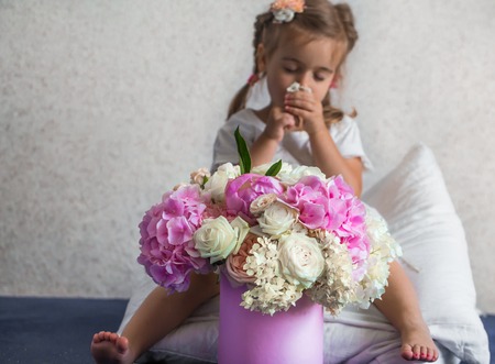 little girl with a big bouquet of fresh flowers, the emotions of a little girl, a girl in a white Board sits on the pillowsの写真素材