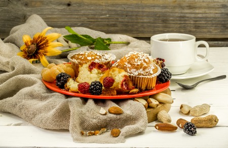 beautiful cupcakes with berries on wooden background in red plate,pichenki in the shape of heartsの写真素材