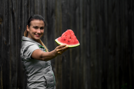 young beautiful girl for a healthy lifestyle, is holding a watermelon on a wooden backgroundの写真素材