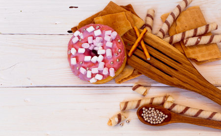 pretty tasty donuts on white wooden background with sweets and wooden utensilsの写真素材