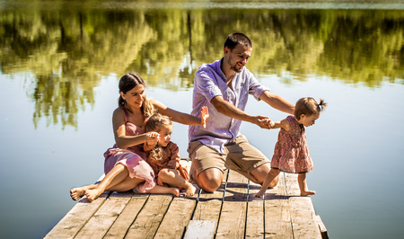 young family on the pier near the lake playing with young daughtersの写真素材