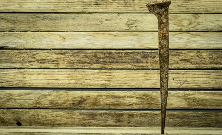 old large rusty nail on wooden backgroundの写真素材