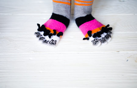 Baby feet in warm, long multicolored socks with toes white backgroundの写真素材