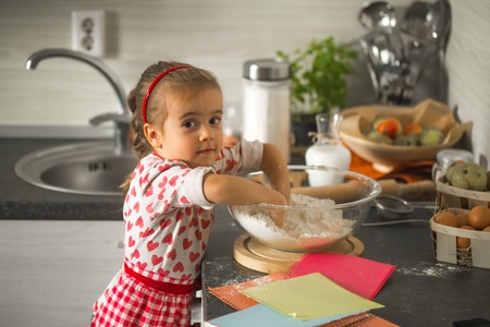 beautiful little girl Baker on kitchen with ingredients for bakingの写真素材