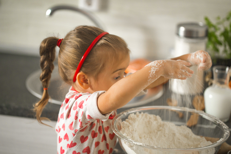 beautiful little girl Baker on kitchen with ingredients for bakingの写真素材