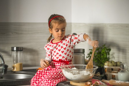 beautiful little girl Baker on kitchen with ingredients for bakingの写真素材