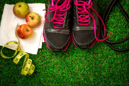sports shoes and equipment on the background of green grass, apples and rouletteの写真素材
