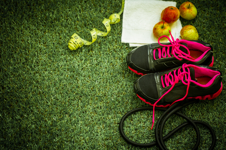 sports shoes and equipment on the background of green grass, apples and rouletteの写真素材