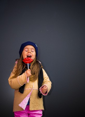 beautiful stylish girl in a black background of the walls, the joyous emotions of the girl, perky girl, big plump lips in the form of candyの写真素材