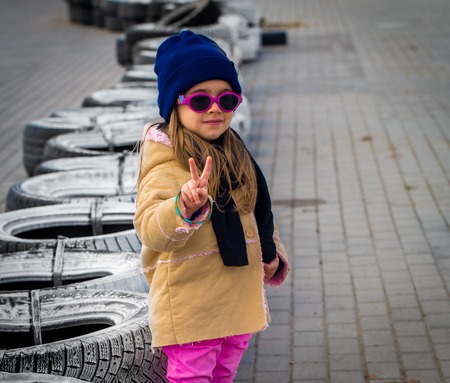 beautiful stylish little girl with glasses on the background of the racing tracks, emotions girlsの写真素材