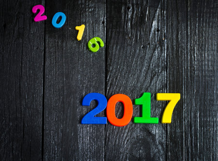 Expiring 2016.New year 2017,multi-colored figures on a wooden black background.