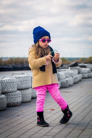 beautiful stylish little girl with glasses on the background of the racing tracks, emotions girlsの写真素材