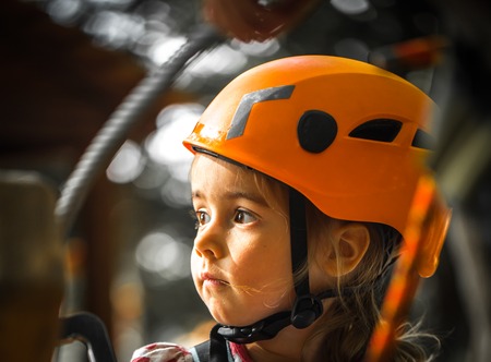 sports happy kid climbs through the ropes, the beautiful girl in the outfit climbing fun in the forest on ropes and different obstaclesの写真素材