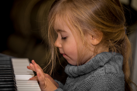 little girl playing on the keys of the piano, closeupの写真素材