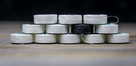 Sewing thread black and white nicely folded on wooden background