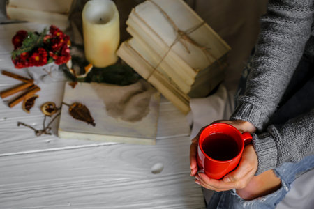 Warm and cozy,and warm concept girl hands with a Cup of tea over white wooden table with book and...