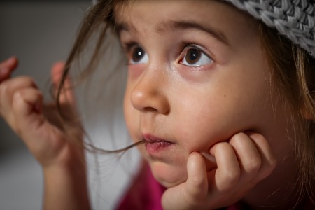portrait of a little beautiful girl in a knitted hat closeupの写真素材