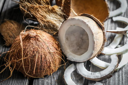 Fresh coconuts broken on wooden background with coconut milk in small glass jarsの写真素材