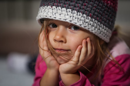 portrait of a little beautiful girl in a knitted hat closeupの写真素材
