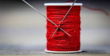 Sewing thread red with two needles closeup on wooden backgroundの写真素材