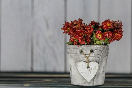 small beautiful pot with a heart and flowers on wooden backgroundの写真素材