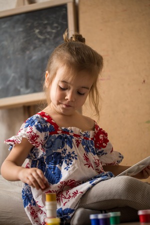 a little girl with colours in hands on the background of the easelの写真素材