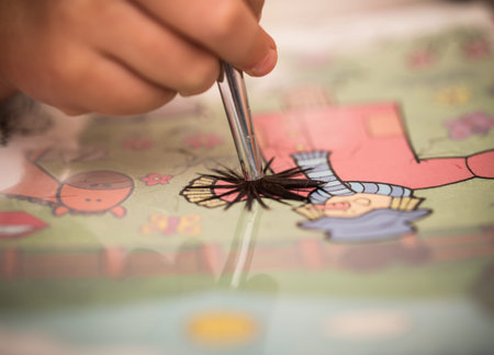 children's hand with a brush paints on white paper with pictures closeup