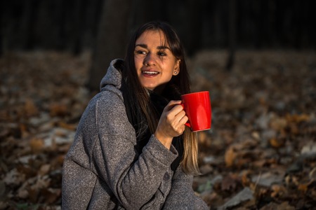 beautiful girl in autumn forest with a hot Cup of tea, autumn conceptの写真素材