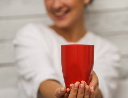 Beautiful young girl dressed in a white jacket with a red Cup in hand,closeup