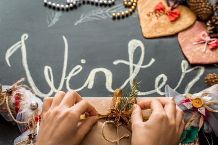 Chalk inscription winter on black chalkboard with Christmas holiday decor toy Christmas gift ,hands tying a ribbon on a box holiday ,holidaysの写真素材