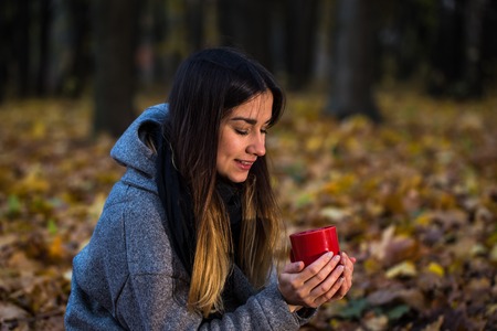 beautiful girl in autumn forest with a hot Cup of tea, autumn conceptの写真素材