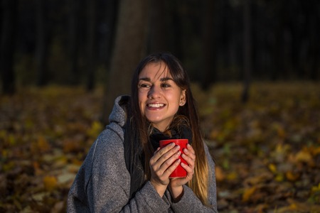 beautiful girl in autumn forest with a hot Cup of tea, autumn conceptの写真素材