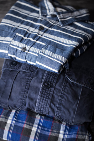 Beautiful stylish men's clothing, shirts folded in a pile on wooden background