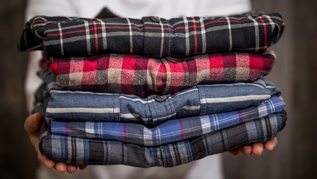 Woman holding a folded shirt in hand,closeup on wooden backgroundの写真素材