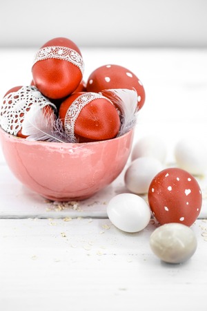 Red Easter eggs on white background tied lace tape , close-up , lie on wooden background, still lifeの写真素材