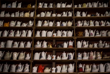 a high wooden stand with a variety of porcelain teapotsの写真素材