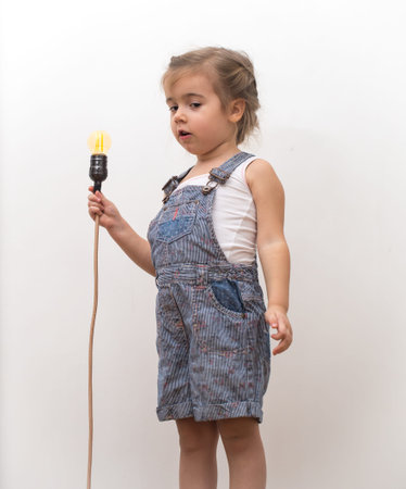 little cute girl with light bulb in hand sitting on the Hank of wires for electricians,concept ideasの写真素材