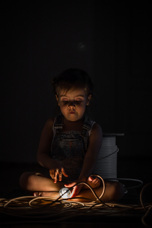 little cute girl with light bulb in hand sitting on the Hank of wires for electricians,concept ideasの写真素材