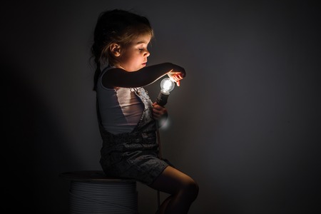 little cute girl with light bulb in hand sitting on the Hank of wires for electricians,concept ideasの写真素材