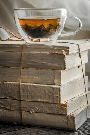 still life Cup of tea stands on the books on wood backgroundの写真素材